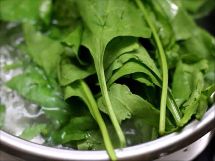 blanching spinach leaves in boiling water.