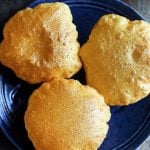 crispy puffed golden pooris served in a ceramic blute plate with potato masala