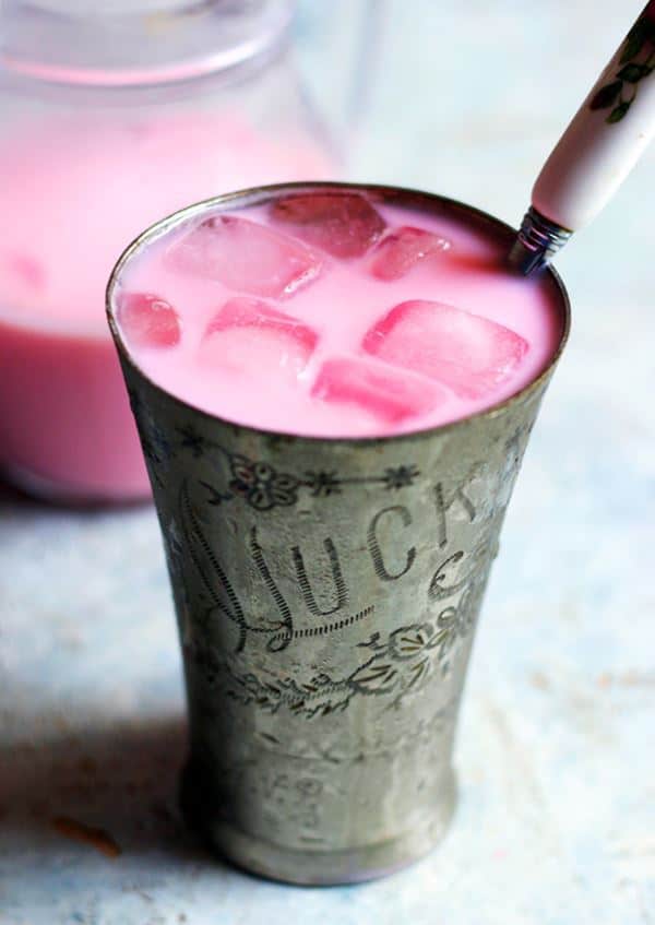 Tall glass of chilled rose milk served with ice cubes