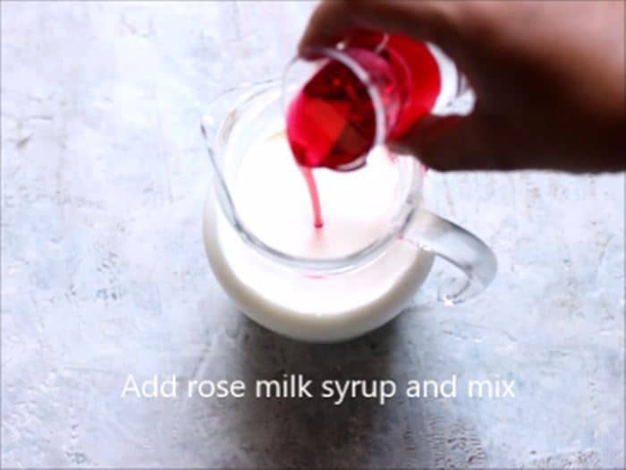Adding rose syrup to chilled milk for rose milk recipe