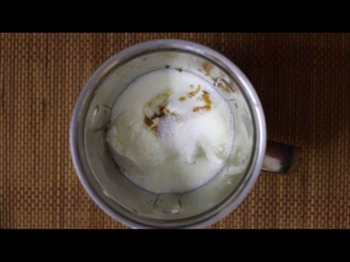 Chilled milk topped with vanilla extract and ice cream for vanilla milkshake