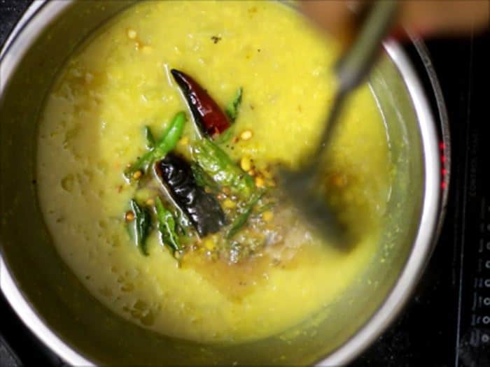 adding tempering to mango dal recipe