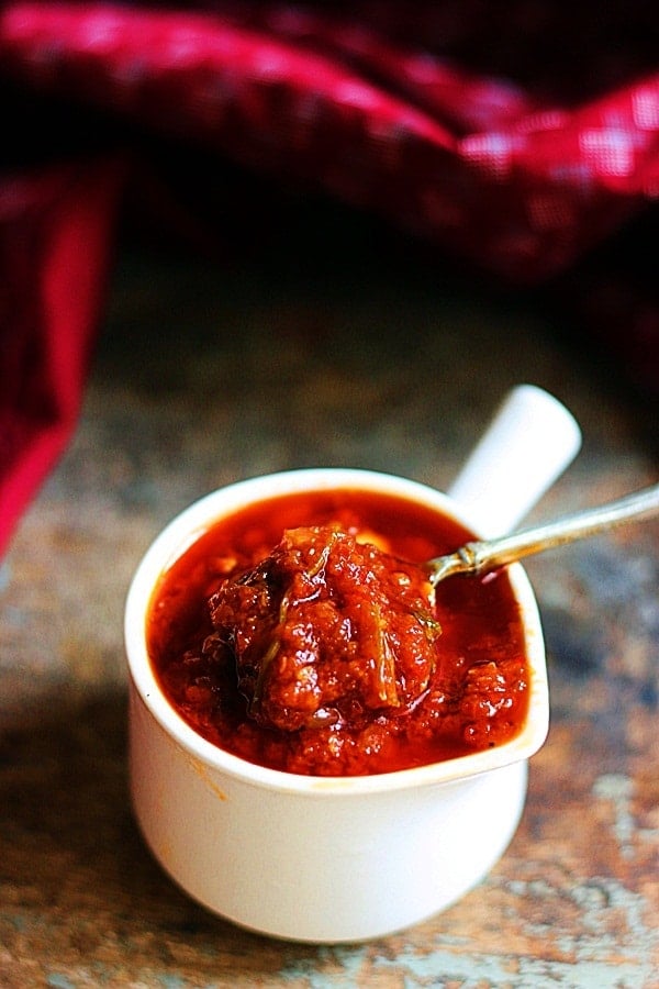 schezwan sauce served in a ceramic cup with a spoon