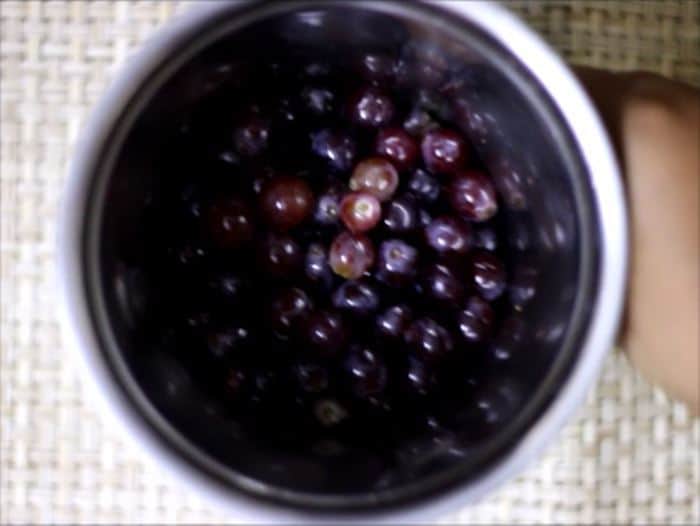 Adding cleaned grapes in a mixer jar for making grape juice