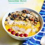 Mango smoothie bowl with assorted toppings served with a spoon