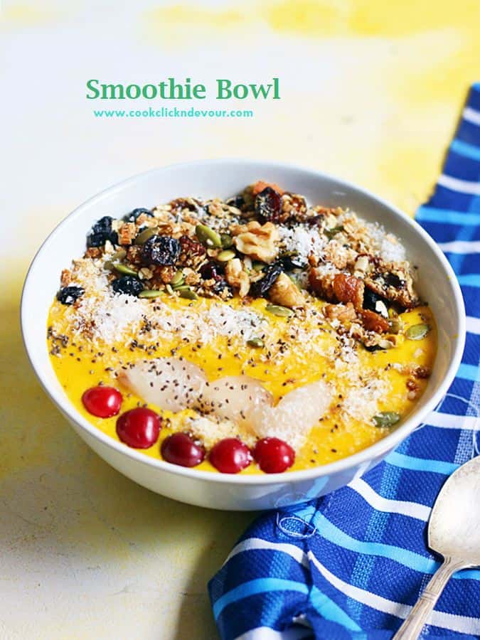 Mango smoothie bowl with assorted toppings served with a spoon