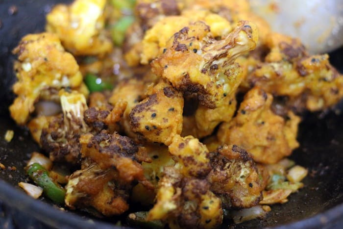 tossing fried gobi in sauce to finish making gobi manchurian