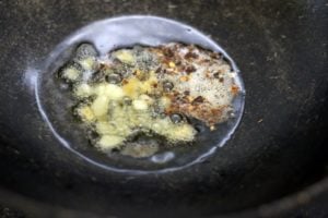 sauteing ginger garlic paste and chilli flakes in sesame oil for gobi manchurian