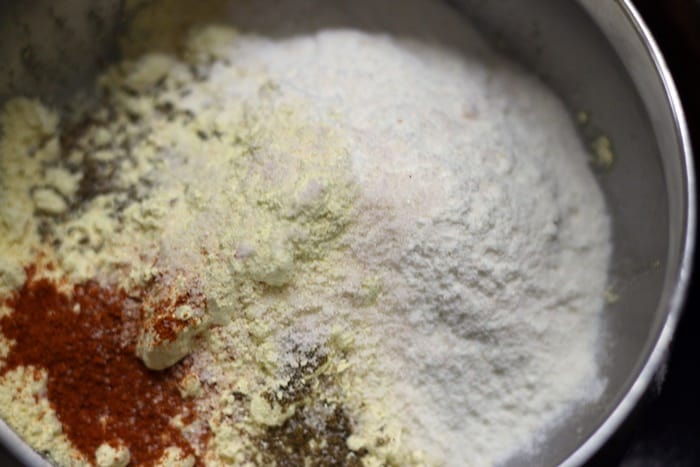 gram flour or besan, rice flour, red choli powder, carom seeds in a mixing bowl