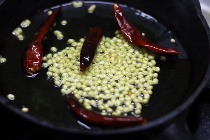 frying chilies and urad dal in oil for making spice paste