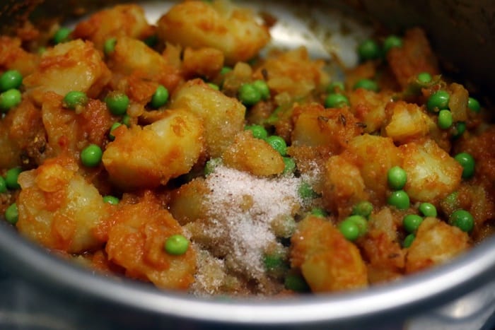 adding cooked peas and potatoes along with salt in making aloo matar recipe