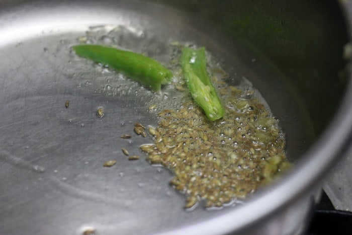 tempering cumin and green chilies for aloo matar recipe