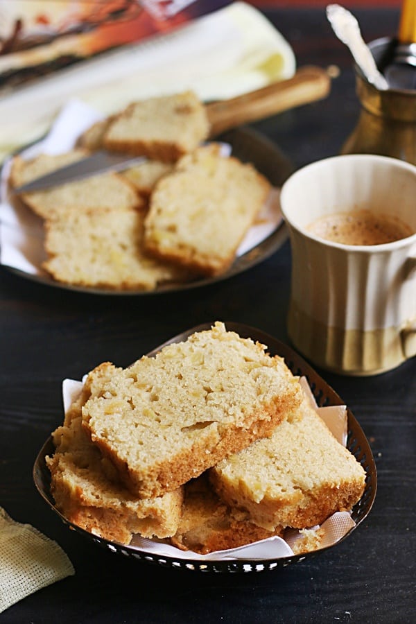 Slices of eggless innamom apple cake stacked in a metal plate served with tea