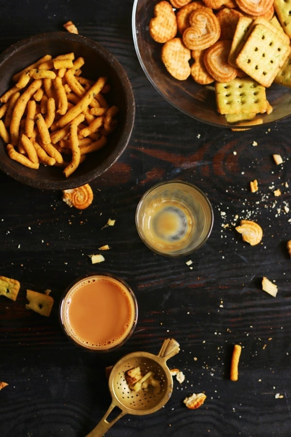 Overhead shot of indian ginger tea or adrak chai served with snacks and biscuits