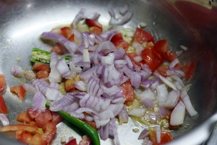 Chopped onions, tomatoes and minced garlic combined in a pressure cooker for Lasooni dal or garlic flavored lentils