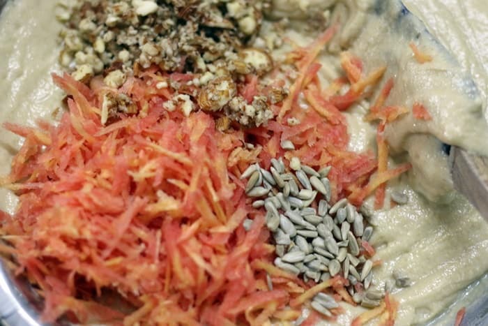 Folding grated carrots, seeds and nuts in the batter for carrot muffins