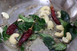 frying curry leaves, red chilies and cashews for bisi bele bath