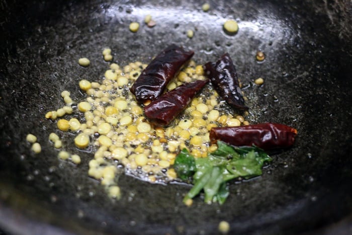 Frying mustard seeds, urad dal, curry leaves, dried chilies in oil- tempering