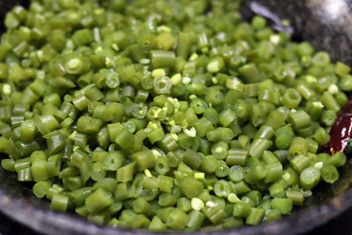 Sauteing the cooked beans for making poriyal