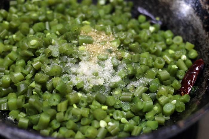 Seasoning beans poriyal with salt and sugar