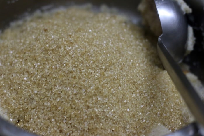 Adding sugar to cooked rava for making pineapple kesari