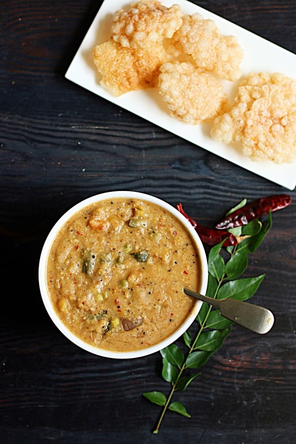 Poricha kootu served in a white bowl with fryums for dinner