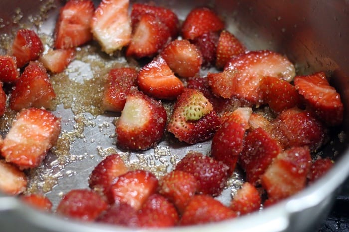 Cooking chopped berries and sugar in a pan