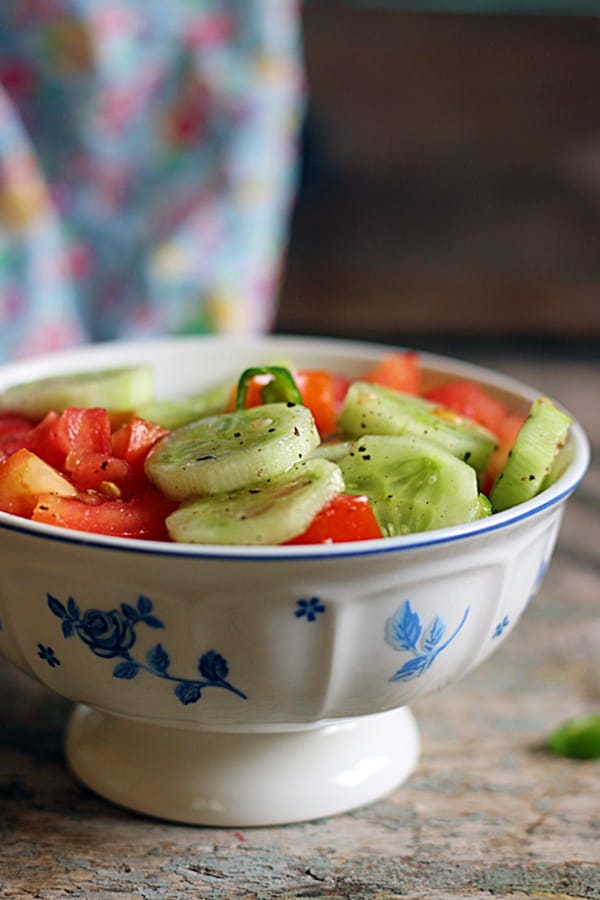 Closeup shot of easy summer tomato cucumber salad served in a footed blue and white bowl
