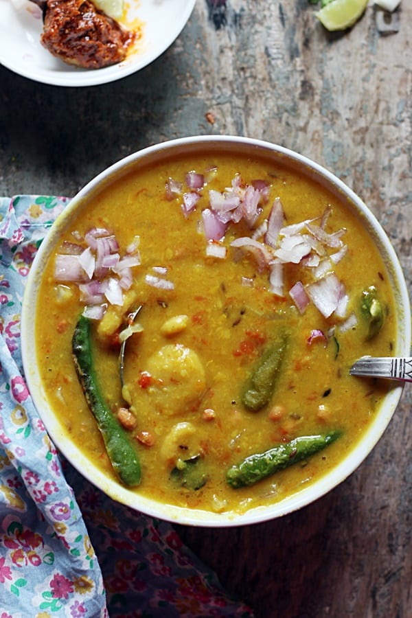 One pot pressure cooker dal dhokli served in a white bowl with a spoon