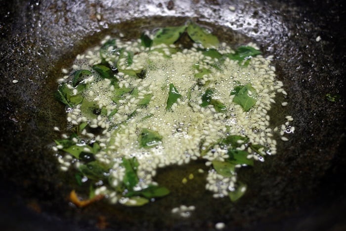 Tempering with mustard seeds, sesame seeds and curry leaves for making handvo recipe