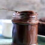 homemade chocolate syrup in a glass bottle served with a spoon