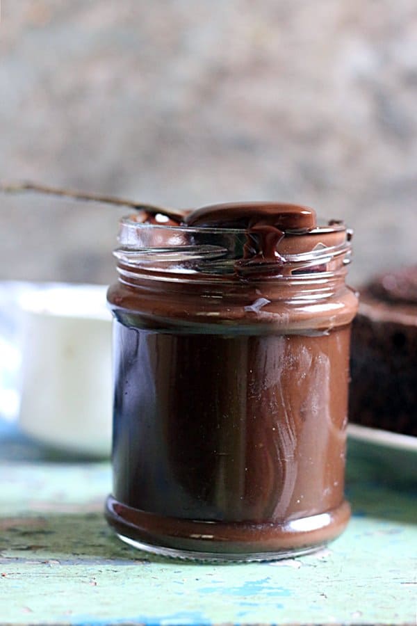 homemade chocolate syrup in a glass bottle served with a spoon 