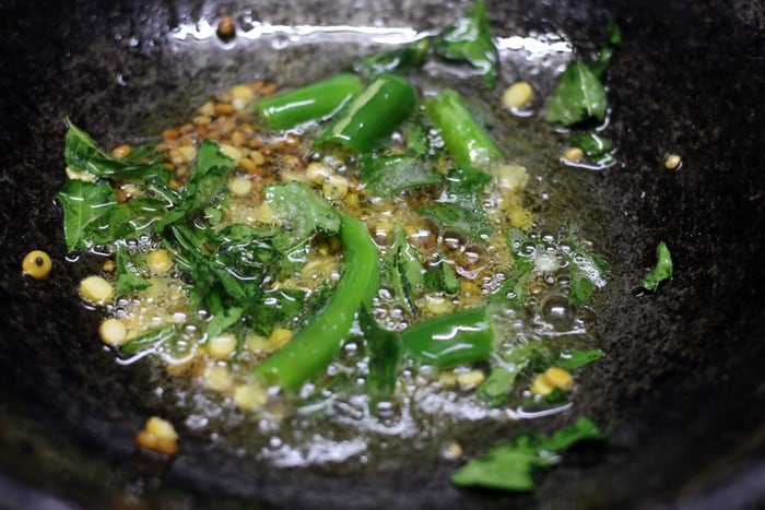 Sauteing lentils, green chilies and curry leaves in oil