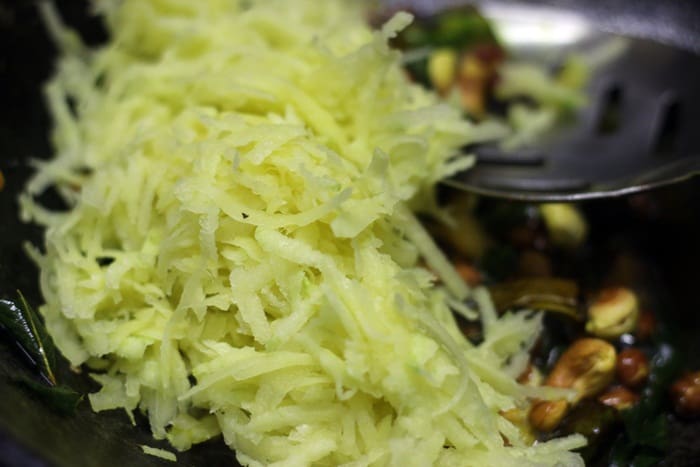 Adding grated raw mangoes to the fried lentils