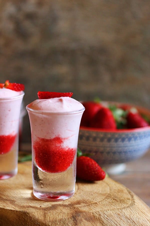 fresh strawberry mousse served in shot glasses served on a wooden tray.