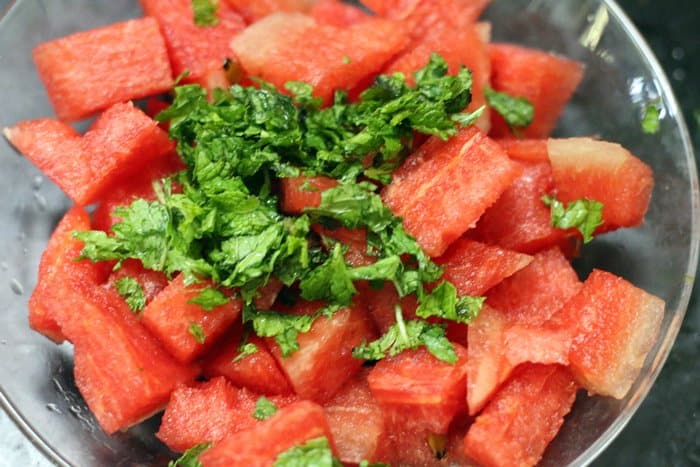 Chopped ripe melon and torn mint leaves in a bowl