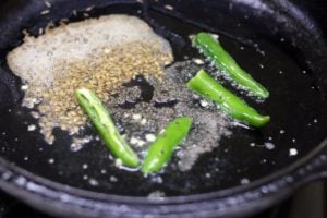 tempering cumin and chilies in oil in a cast iron pan