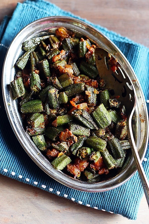 restaurant style bhindi masala served in a steel plate with a spoon