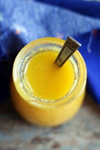 Homemade ghee in a small glass jar with a spoon