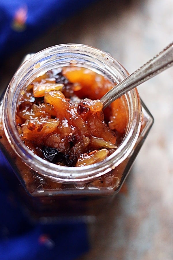 Pineapple chutney stored in a glass jar with a spoon
