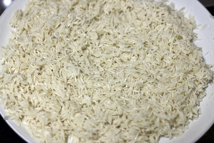 soaked and drained long grain rice spread on a plate
