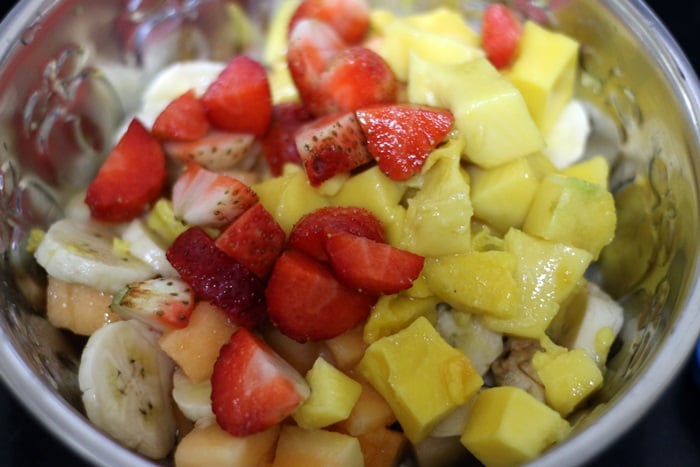 Mixed cut fruits- banana, strawberries and mangoes in a silver bowel.