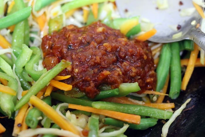 Schezwan sauce added to chopped vegetables