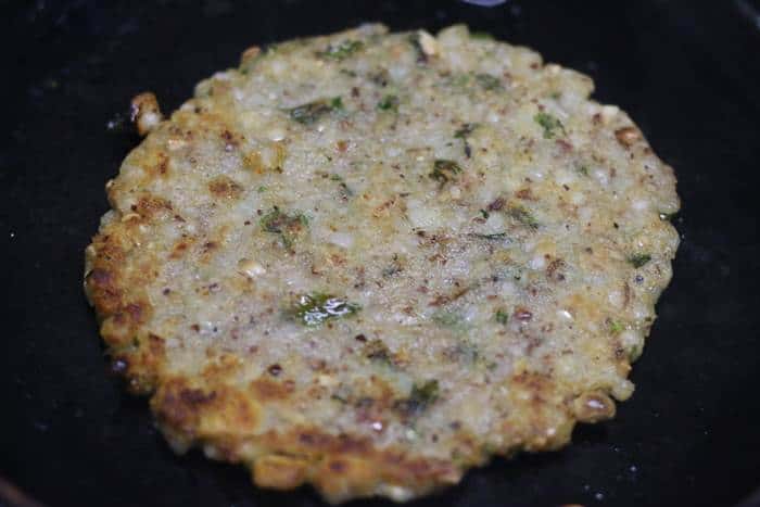 crispy sabudana thalipeeth fried in cast iron pan.
