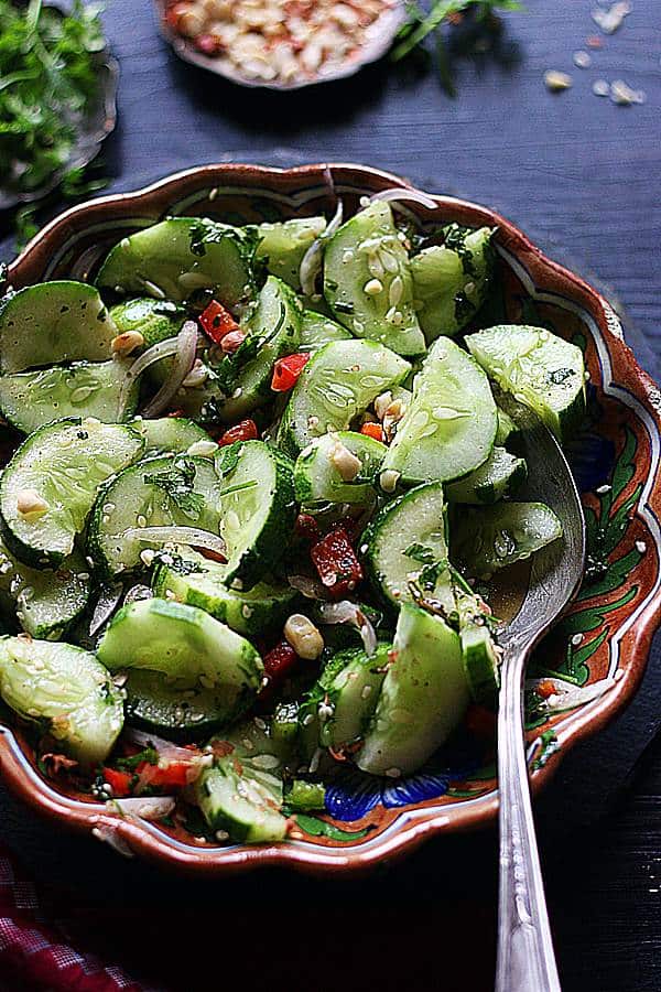 Asian cucumber salad served in a brown footed bowl with a spoon