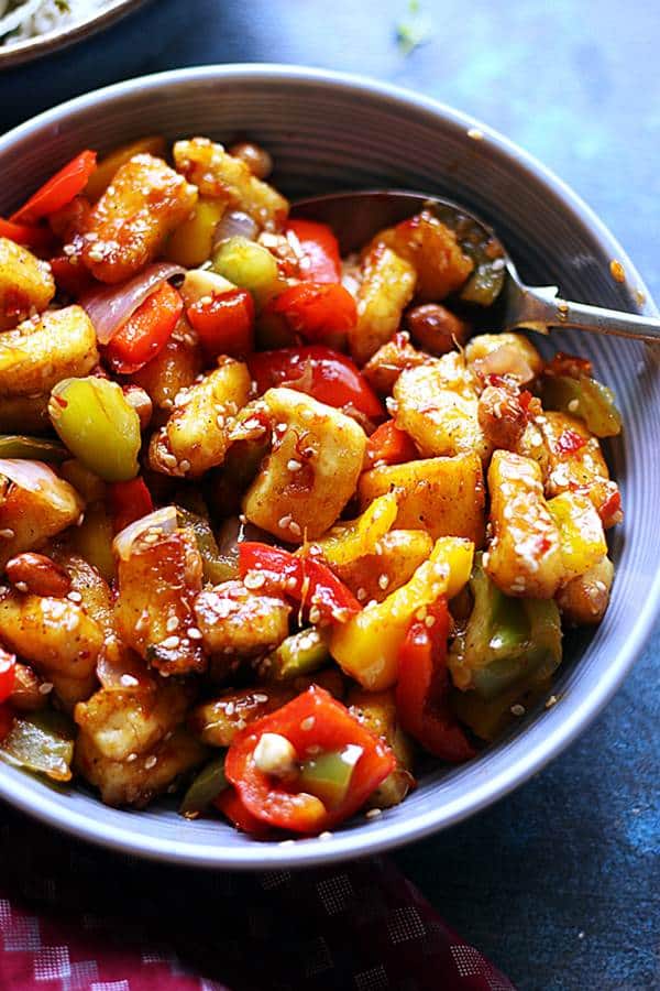 Crispy delicious kung pao tofu served in a ceramic bowl with a spoon.