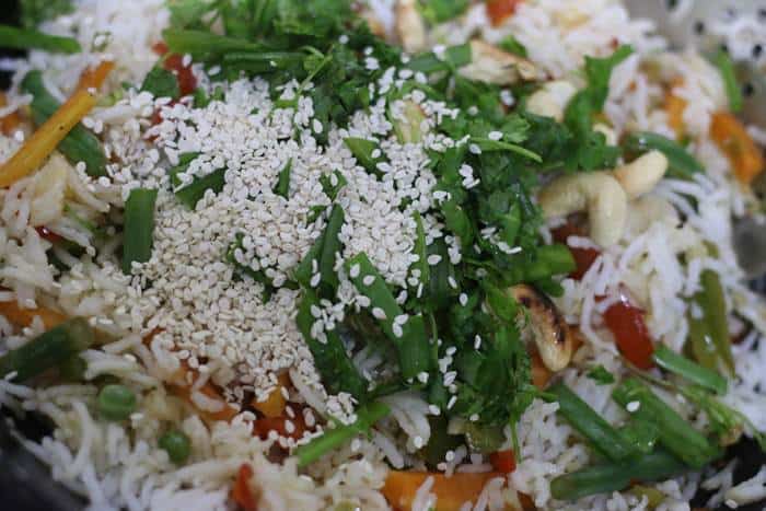 basil leaves cilantro leaves, cashews and sesame seeds added as topping for fried rice