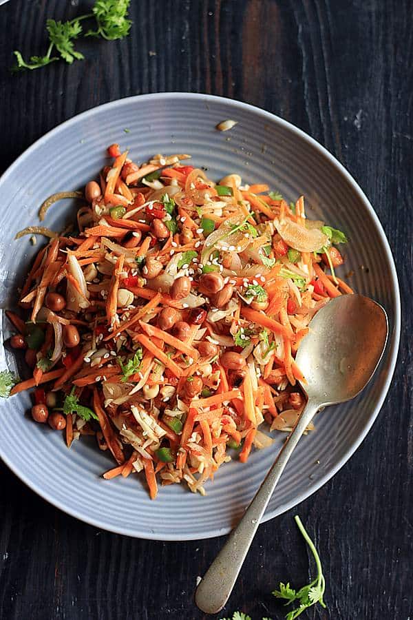 Carrot salas with thai style dressing in a ceramic plate with a spoon.