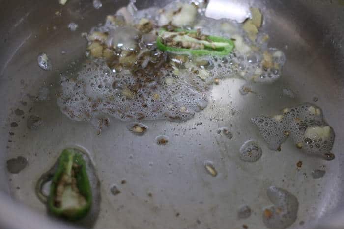 sauteing cumin seeds, green chilies in oil