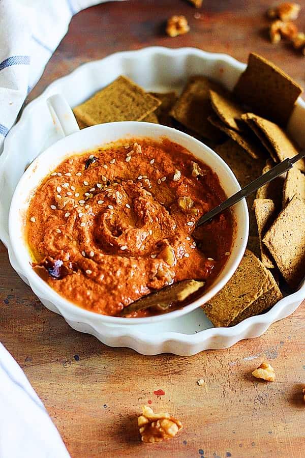 muhammara served with crackers in a white ceramic plate and bowl.